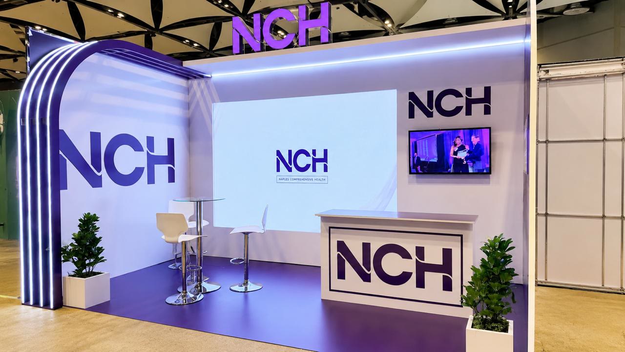 Stand de marca NCH con recepción, pantalla principal, iluminación arquitectónica y espacios de atención