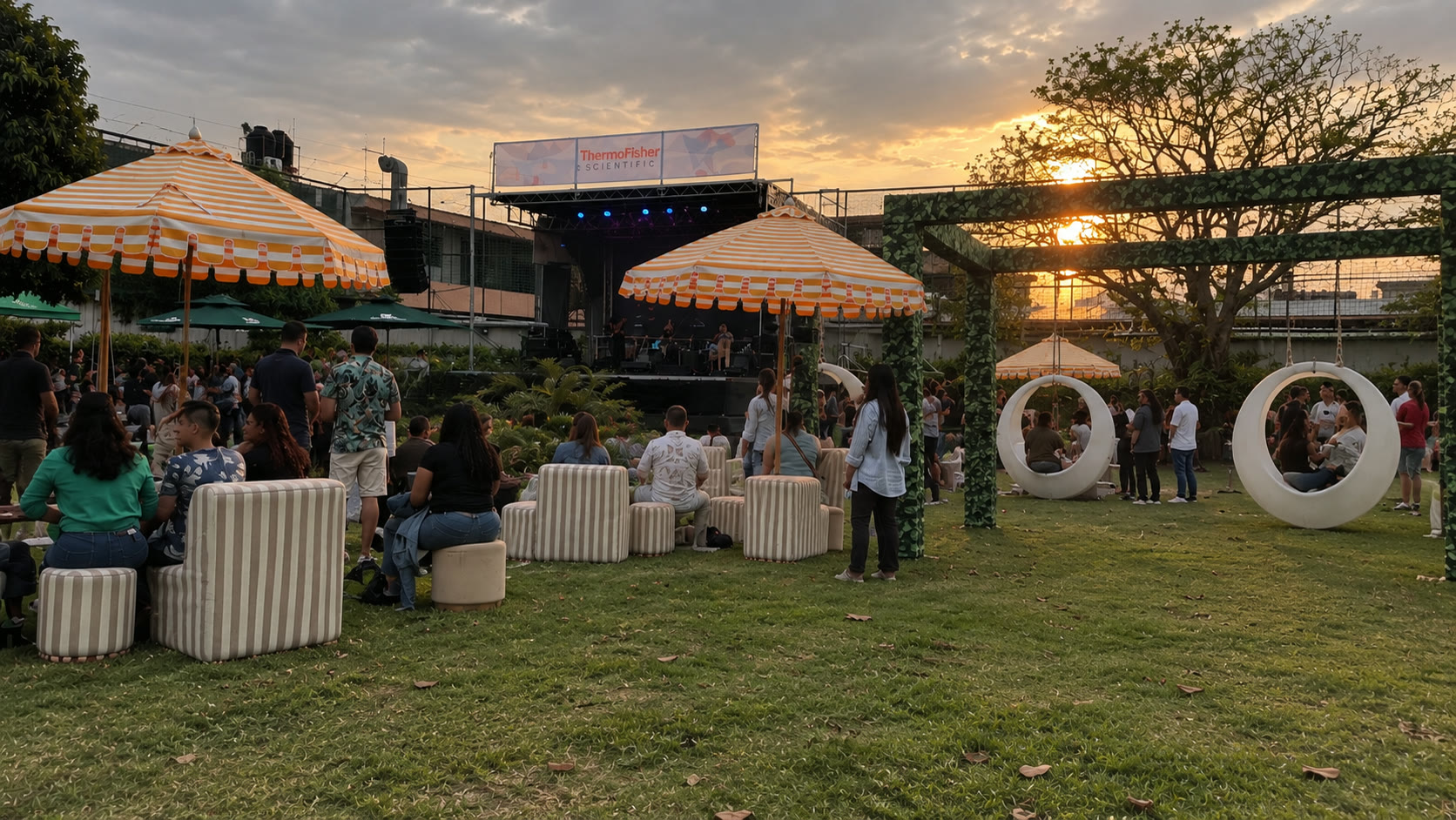 Evento social al aire libre de Thermo Fisher Scientific con escenario, asistentes y ambientación de jardín al atardecer